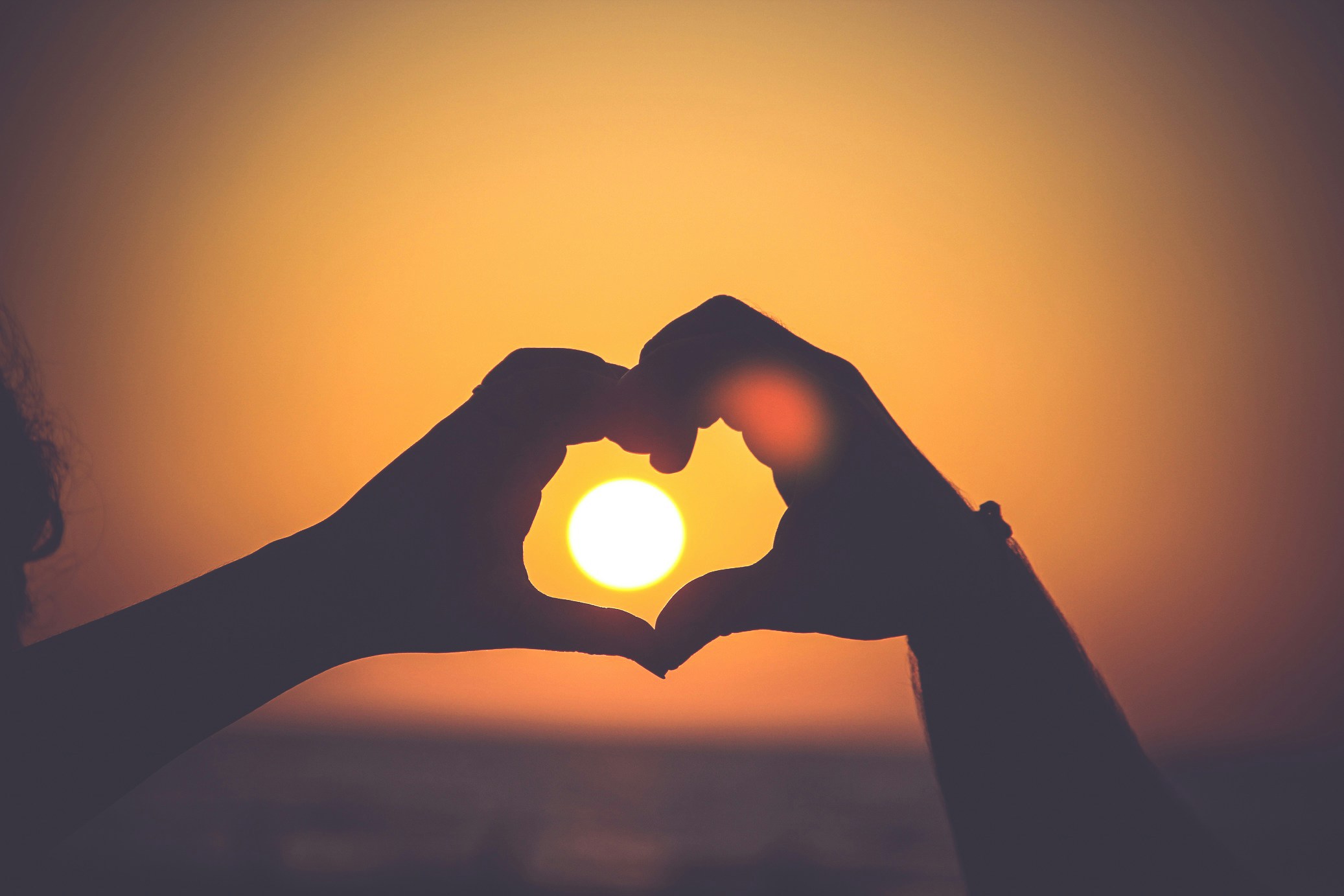 Two hands forming a heart shape against a sunset Two hands forming a heart shape against a sunset, symbolizing love and connection, perfect for romantic or inspirational content.